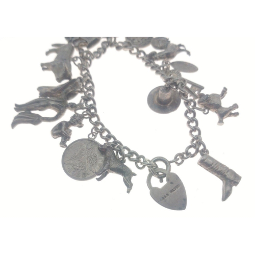 22 - A charm bracelet with a locket stamped silver hosting 14 charms some stamped silver, Weight 48.65g a... 