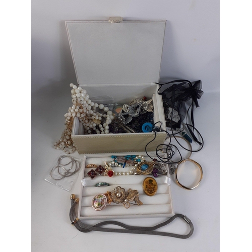 32 - An attractive cream leather jewellery case  containing a super mixture of costume jewellery.  Lots o... 