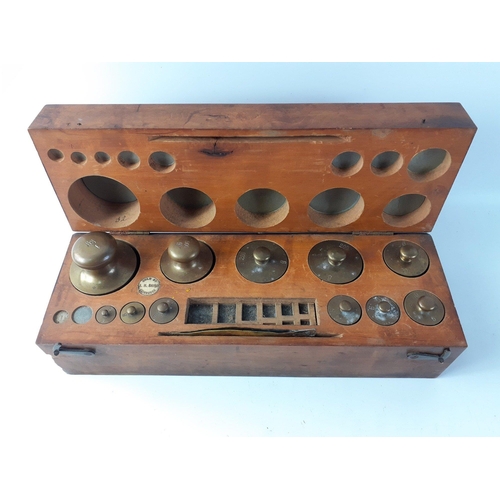 584 - A vintage wooden box sold by AH BAIRD of Edinburgh, containing apothecary weights from 2g - 1kg (2 s... 