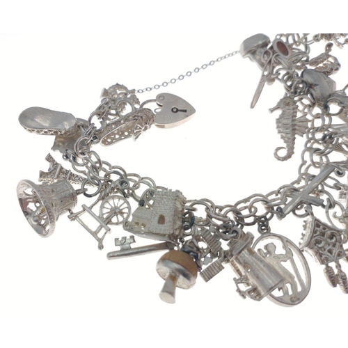 104 - A silver charm bracelet with lots of charms - weight gross 67.65g approx#113