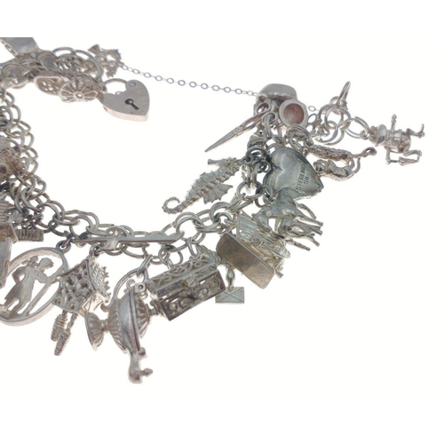 104 - A silver charm bracelet with lots of charms - weight gross 67.65g approx#113