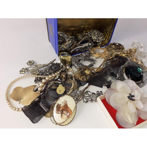 26 - A small tin of costume jewellery including some large brooches#26