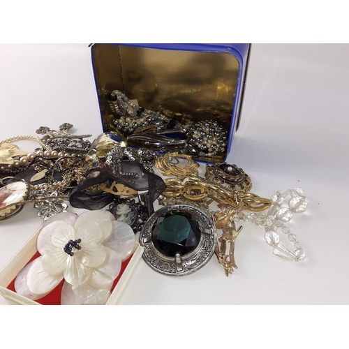 26 - A small tin of costume jewellery including some large brooches#26