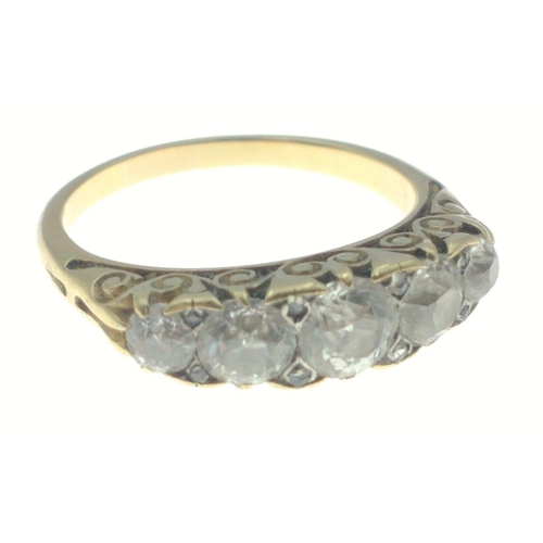 7 - An unmarked yellow metal ring with elaborate shoulder design with 5 mid-cut substantial clear stones... 