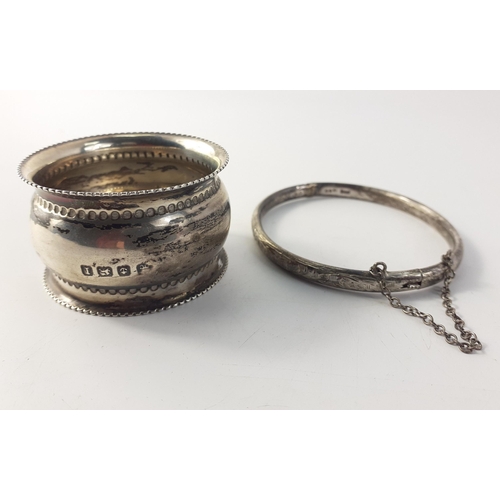 83 - A silver hallmarked bangle with safety chain, (Chester? 1956) weight 7g approx, and a silver napkin ... 