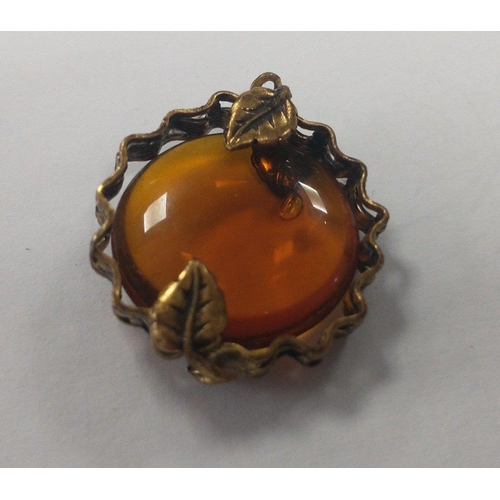 11 - A vintage pendant with an amber bead 20mm x20mm set in a yellow metal surround held in with 4 leaves... 