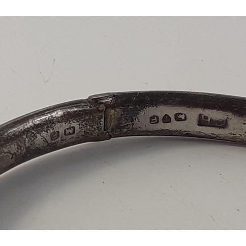 53 - A silver hallmarked bangle with safety chain, (Chester? 1956) weight 7g approx, and a silver napkin ... 
