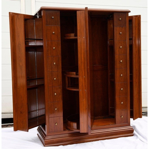 195 - A Chinese rosewood revolving bar in an Art Deco style, it houses various compartments for bottles, g... 