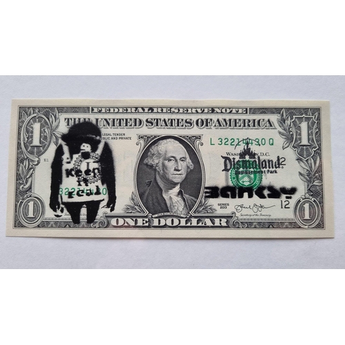 6 - A framed stencilled DISMALAND real One Dollar bill stamped with the BANKSY chomp along with a stenci... 