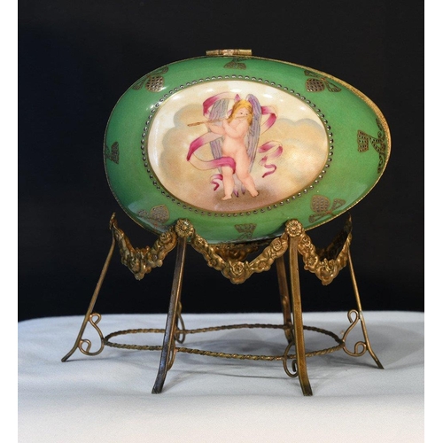 86 - A painted porcelain egg on metal brass-coloured stand. H: 18cm  W: 18cm  D: 13cm#86