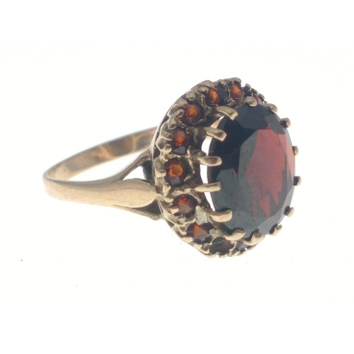 22 - A 9ct fully hallmarked gold ring with large red centre stone and surrounding similar small stones (o... 