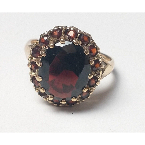 22 - A 9ct fully hallmarked gold ring with large red centre stone and surrounding similar small stones (o... 