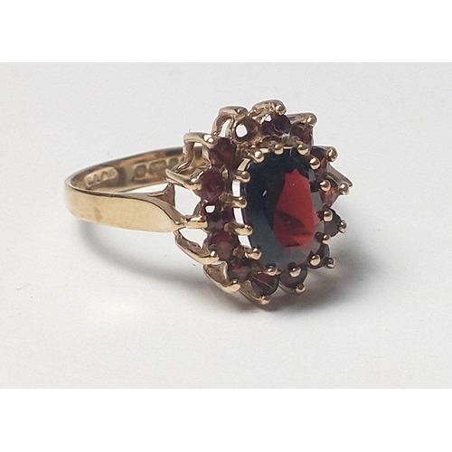 23 - A 375 fully hallmarked gold ring with large centre stone with surrounding red stones (one missing). ... 