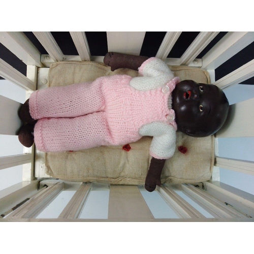 156 - A small black doll with bisque head and cloth limbs in modern dress, standing 37cm high.  Comes with... 