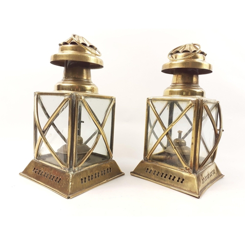 433 - A pair of decorative brass storm lanterns, glass intact and with wicks, each standing approx 26cm hi... 