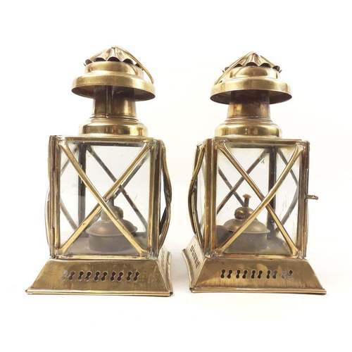 433 - A pair of decorative brass storm lanterns, glass intact and with wicks, each standing approx 26cm hi... 