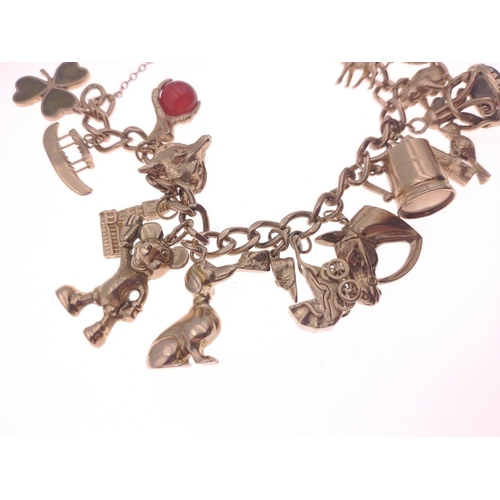 25 - A 375 stamped gold chain bracelet with padlock with no fewer than 19 charms to include a horse, hors... 