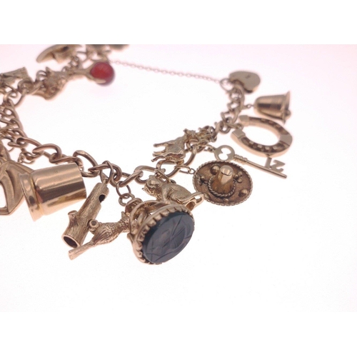 25 - A 375 stamped gold chain bracelet with padlock with no fewer than 19 charms to include a horse, hors... 