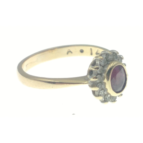 27 - A 9ct hallmarked gold ring set with 14 small diamonds (tested) and a centre red stone, size I, gross... 