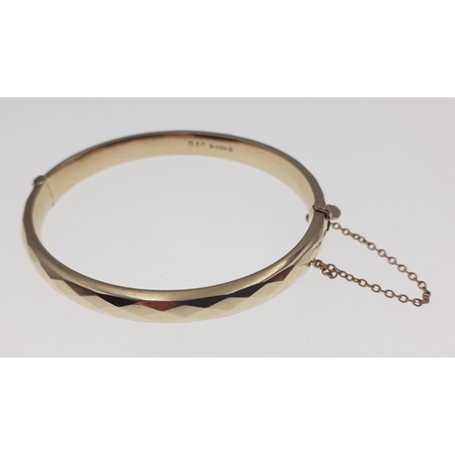 58 - A snap-shut gold bangle with safety chain hallmarked for Birmingham and stamped 375, interior dia. 6... 