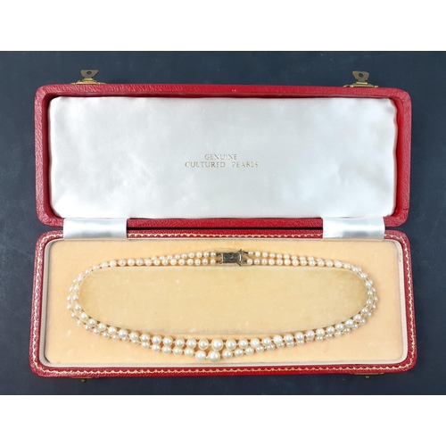 77 - A plush red box containing a double string of cultured pearls with a 9ct stamped gold clasp.  A qual... 