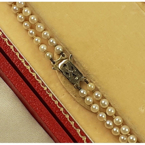 77 - A plush red box containing a double string of cultured pearls with a 9ct stamped gold clasp.  A qual... 