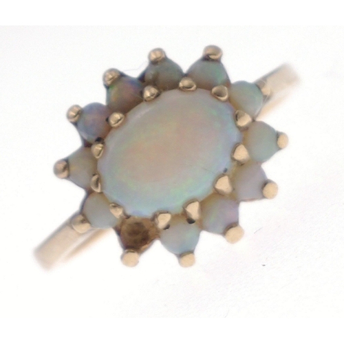 8 - A 9ct hallmarked opal ring set with large central stone (9mm x 5mm approx) and surrounded by 11 smal... 