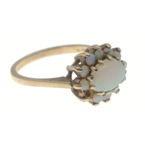 8 - A 9ct hallmarked opal ring set with large central stone (9mm x 5mm approx) and surrounded by 11 smal... 