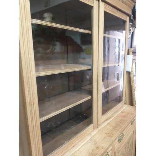 386 - An imposing natural wood dresser with glazed upper with 3 shelves, 2 drawers and a 2 door carved bot... 