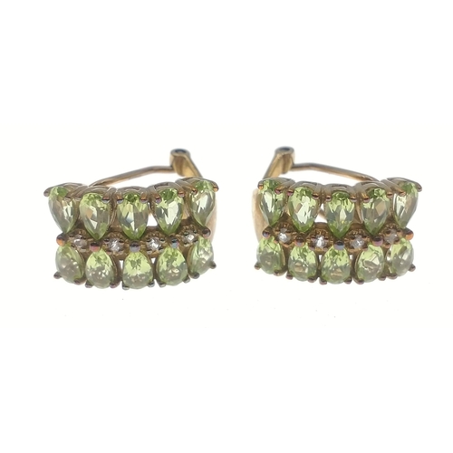 33 - A pair of 375 stamped gold clip-on earrings each set with 10 oval cut peridots and 4 small central d... 