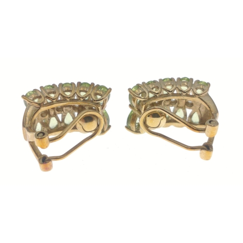 33 - A pair of 375 stamped gold clip-on earrings each set with 10 oval cut peridots and 4 small central d... 