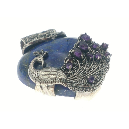 82 - A silver pendant stamped 925 TGGC with a silver peacock with purple stones in his tail encapsulating... 
