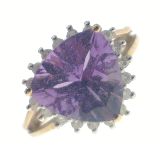 9 - A gold ring hallmarked 9K with a trillion cut central amethyst surrounded by 18 small diamonds (test... 
