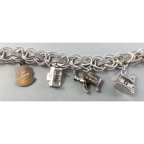 79 - A rather lovely silver charm bracelet with 7 silver charms including a bus, clog, church, and others... 