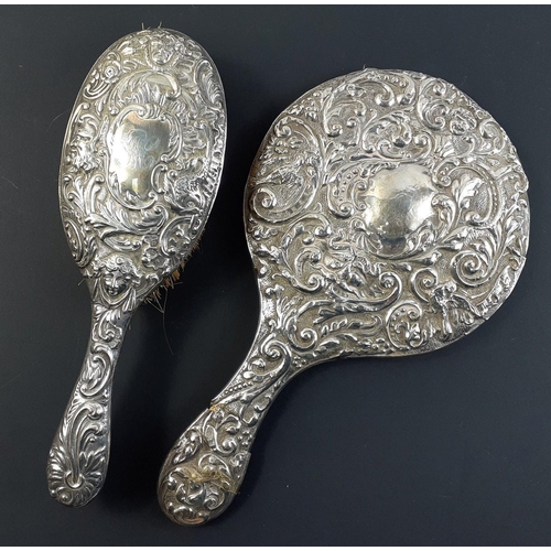 47A - An antique silver dressing table mirror and hairbrush heavily decorated with London 1895 hallmarks, ... 