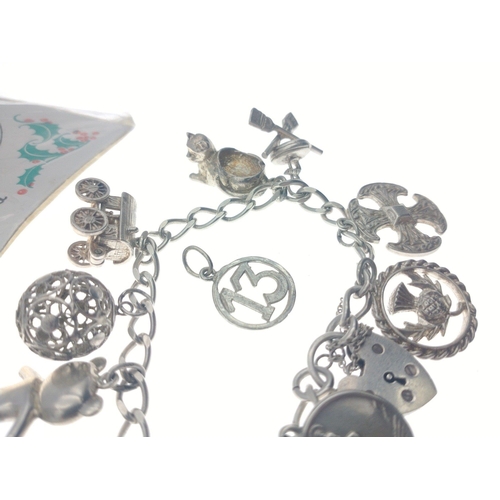 246 - A small sterling silver charm bracelet with some silver and white metal charms with some additional ... 