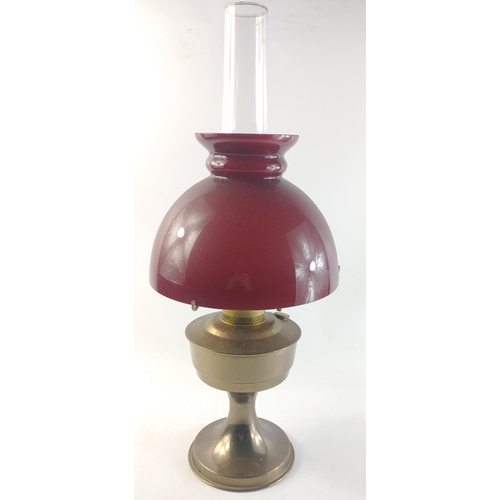 176 - A large brass oil lamp with a crimson glass shade standing 47cm high, excluding chimney.#177