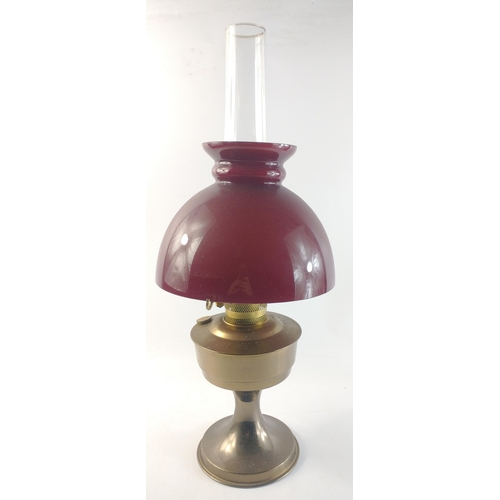 176 - A large brass oil lamp with a crimson glass shade standing 47cm high, excluding chimney.#177