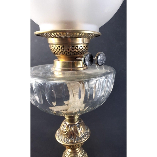 202 - Substantial embossed brass based oil lamp with chimney and globe shade. Burner dials marked with sai... 