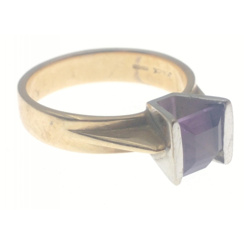 28 - A 375 hallmarked yellow gold ring set with amethyst flanked with white gold. Stone has a slight chip... 