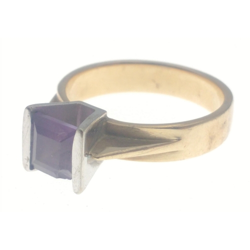 28 - A 375 hallmarked yellow gold ring set with amethyst flanked with white gold. Stone has a slight chip... 