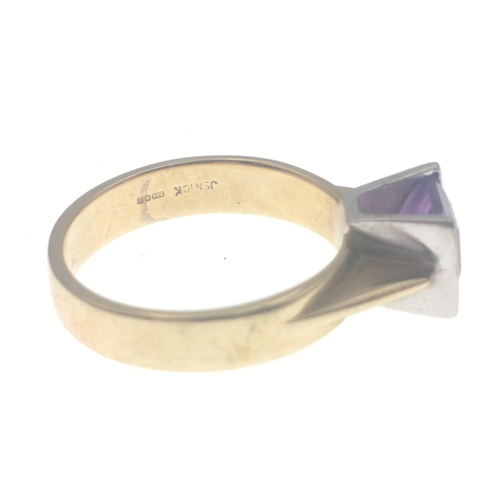 28 - A 375 hallmarked yellow gold ring set with amethyst flanked with white gold. Stone has a slight chip... 