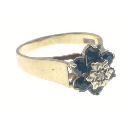 29 - Hallmarked 375 yellow gold ring with central diamond (tested) surrounded by 6 dark coloured blue sto... 