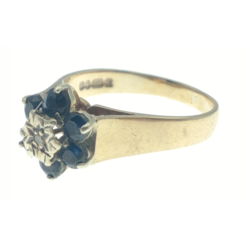 29 - Hallmarked 375 yellow gold ring with central diamond (tested) surrounded by 6 dark coloured blue sto... 