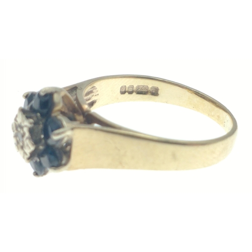 29 - Hallmarked 375 yellow gold ring with central diamond (tested) surrounded by 6 dark coloured blue sto... 