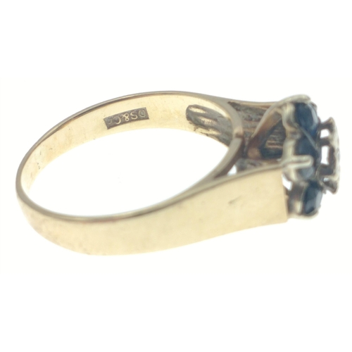 29 - Hallmarked 375 yellow gold ring with central diamond (tested) surrounded by 6 dark coloured blue sto... 