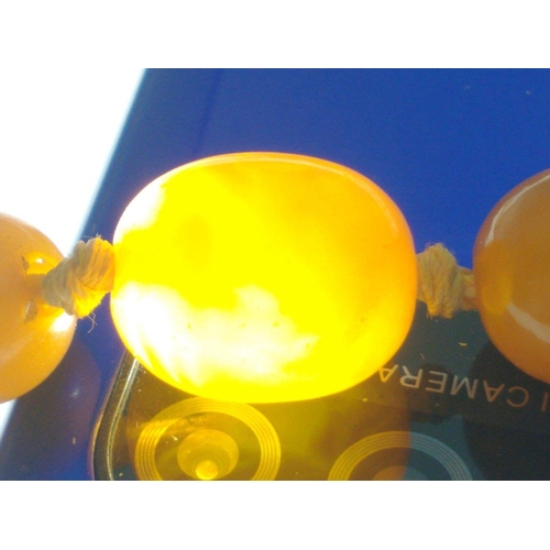 71 - A string of graduated butterscotch amber-style  beads 60cm long approx, weight 29g approx. Note one ... 