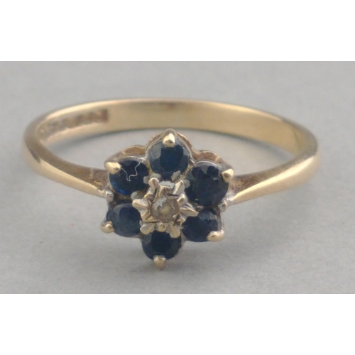 26 - A 375 hallmarked 9ct gold ring with small diamond centre stone and six sapphire surrounds. Size P Gr... 