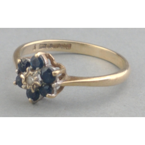 26 - A 375 hallmarked 9ct gold ring with small diamond centre stone and six sapphire surrounds. Size P Gr... 