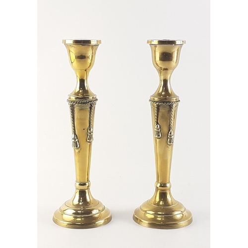 66 - A pair of very attractive brass candlesticks with tassel rope adornments. Each stands 25cm high. In ... 